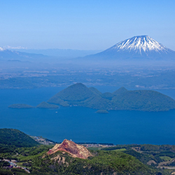 Vue sur le lac Tôya 洞爺湖 et les volcans environnants dont le Shôwa-shinzan 昭和新山 tout en bas de l’image © Tsukioka Yôichi 月岡陽一www.tsukioka-world.com Vue sur le lac Tôya 洞爺湖 et les volcans environnants dont le Shôwa-shinzan 昭和新山 tout en bas de l’image © Tsukioka Yôichi 月岡陽一www.tsukioka-world.com